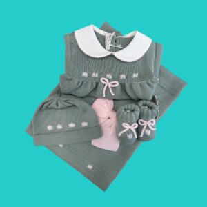 Folded teal knit baby outfit with white collar and pink bow, embroidered flowers, on turquoise background (product photo)