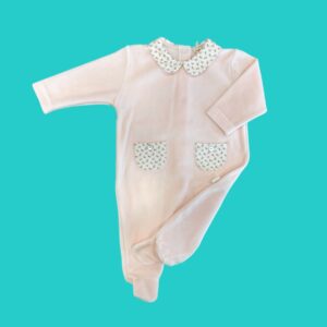 Pink baby onesie with a floral-patterned collar and matching pockets, laid flat on a turquoise background for display.